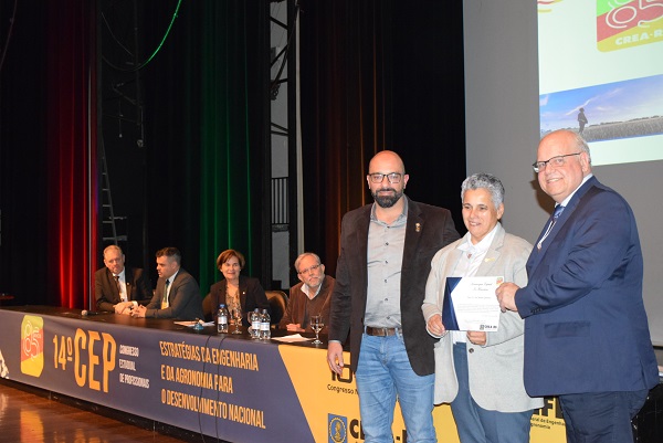 Eng. Civil Lia Maria Herzer Quintana,  filha do homenageado, recebeu a homenagem do Eng. Paulo Guimarães, diretor-presidente da Mútua nacional, e do Eng. Civil Marcio Marum, coordenador da Civil do CREA-RS